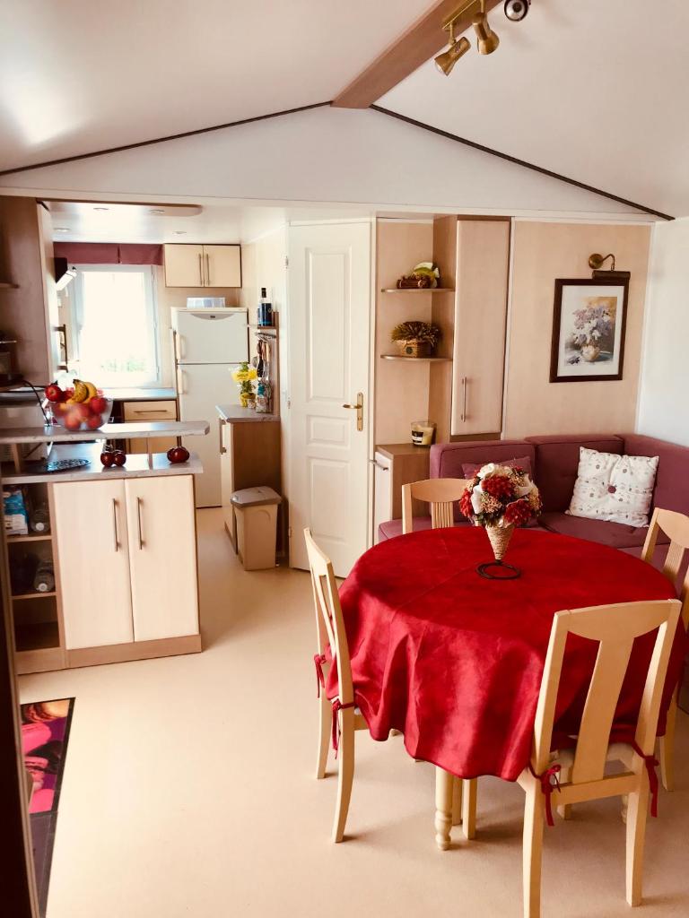 une cuisine et une salle à manger avec une table et des chaises rouges dans l'établissement MOBIL HOME PLAGE DE PAMPELONNE SUR UN TRES BEL EMPLACEMENT SURPLOMBANT LA BAIE DE PAMPELONNE, à Saint-Tropez 5 autres photos