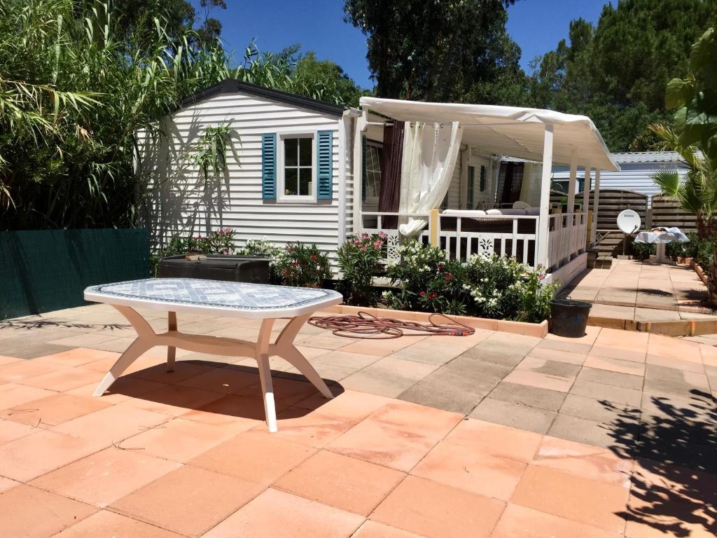 un patio avec une table devant une maison dans l'établissement MOBIL HOME PLAGE DE PAMPELONNE SUR UN TRES BEL EMPLACEMENT SURPLOMBANT LA BAIE DE PAMPELONNE, à Saint-Tropez
