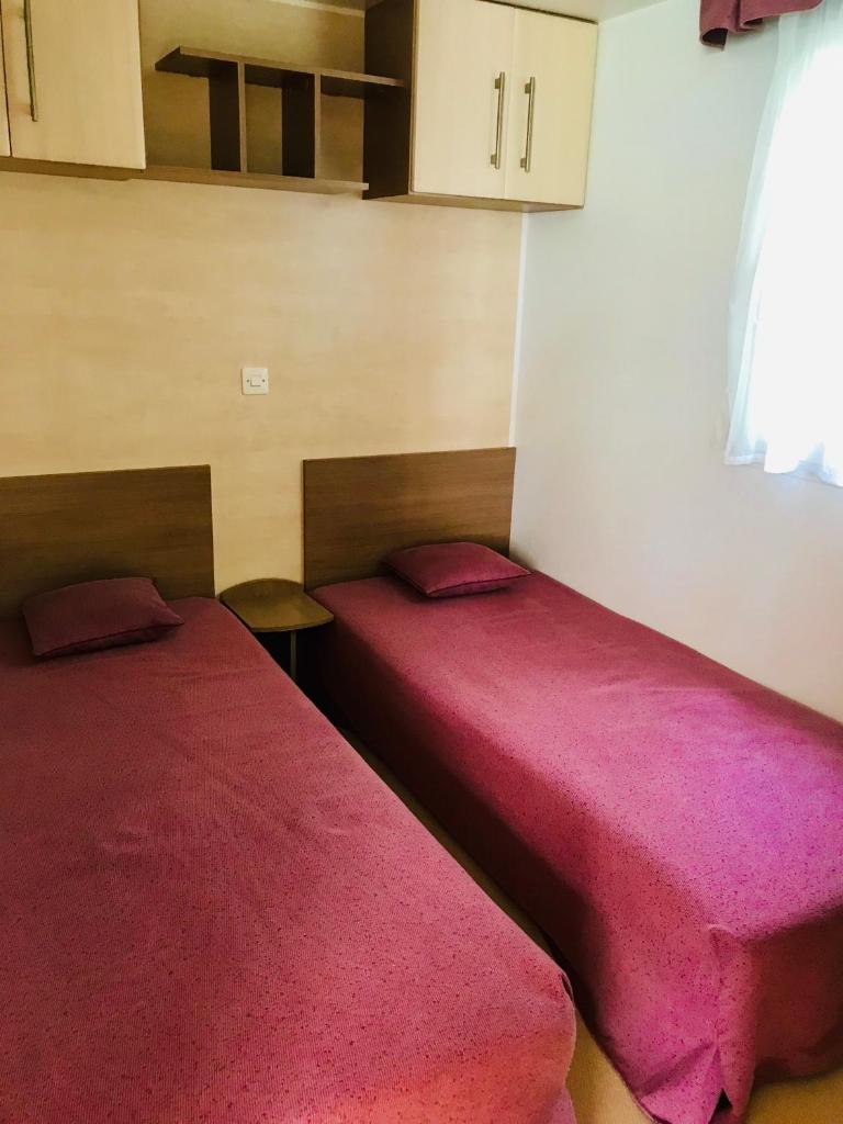 - 2 lits dans une chambre avec des couvertures rouges dans l'établissement MOBIL HOME PLAGE DE PAMPELONNE SUR UN TRES BEL EMPLACEMENT SURPLOMBANT LA BAIE DE PAMPELONNE, à Saint-Tropez