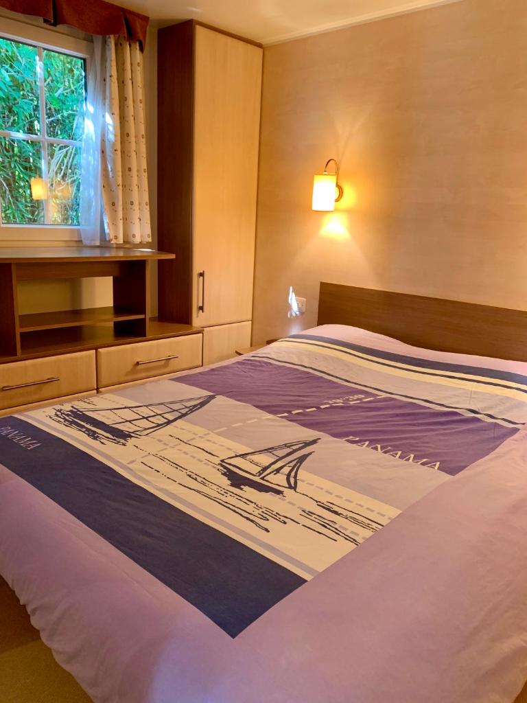 un grand lit dans une chambre avec une fenêtre dans l'établissement MOBIL HOME PLAGE DE PAMPELONNE SUR UN TRES BEL EMPLACEMENT SURPLOMBANT LA BAIE DE PAMPELONNE, à Saint-Tropez