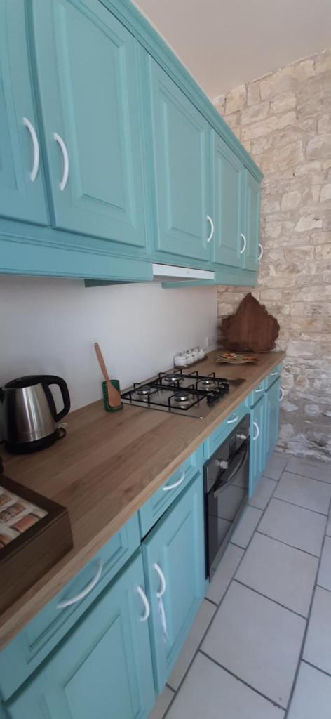 La cuisine est équipée de placards bleus et d'un four avec plaques de cuisson. dans l'établissement Gite le mûrier blanc, à Accolay