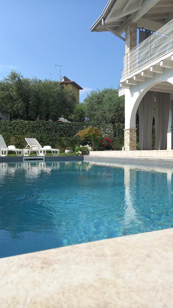 - une piscine avec 2 chaises et un pont dans l'établissement Villa Bocciolo del Garda, à Manerba del Garda
