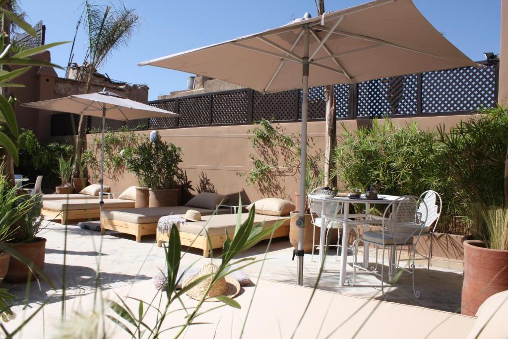 un patio avec une table, des chaises et un parasol dans l'établissement Riad Olema et Spa, à Marrakech