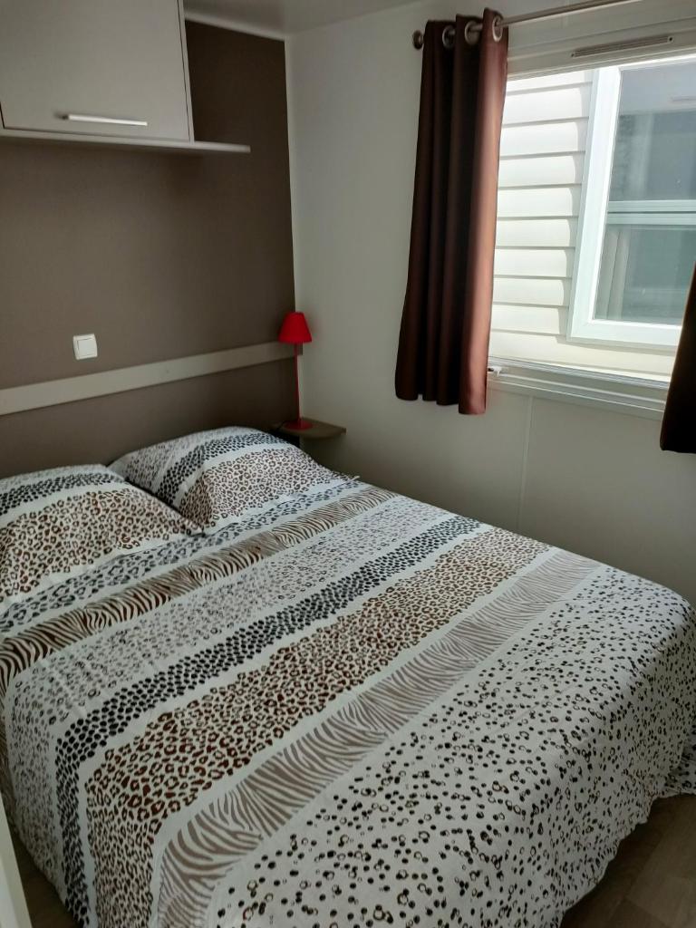 - un lit dans une chambre avec fenêtre dans l'établissement Mobil-home Siblu Les Rives de Condrieu, à Condrieu