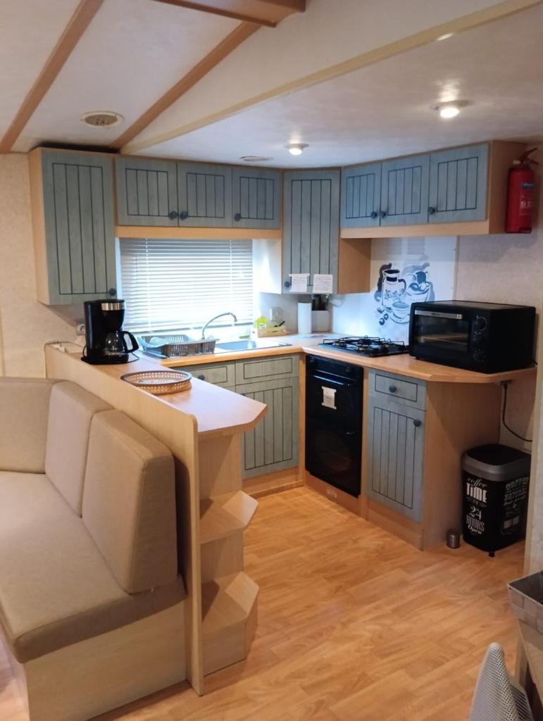 La cuisine est équipée de placards bleus et d'un four avec plaques de cuisson. dans l'établissement Mobil home Gassin, à Gassin 4 autres photos