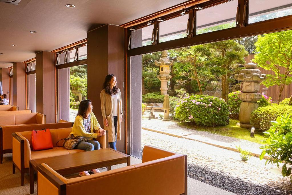 deux femmes debout dans un hall donnant sur une fenêtre dans l'établissement Ooedo Onsen Monogatari Awara, à Awara