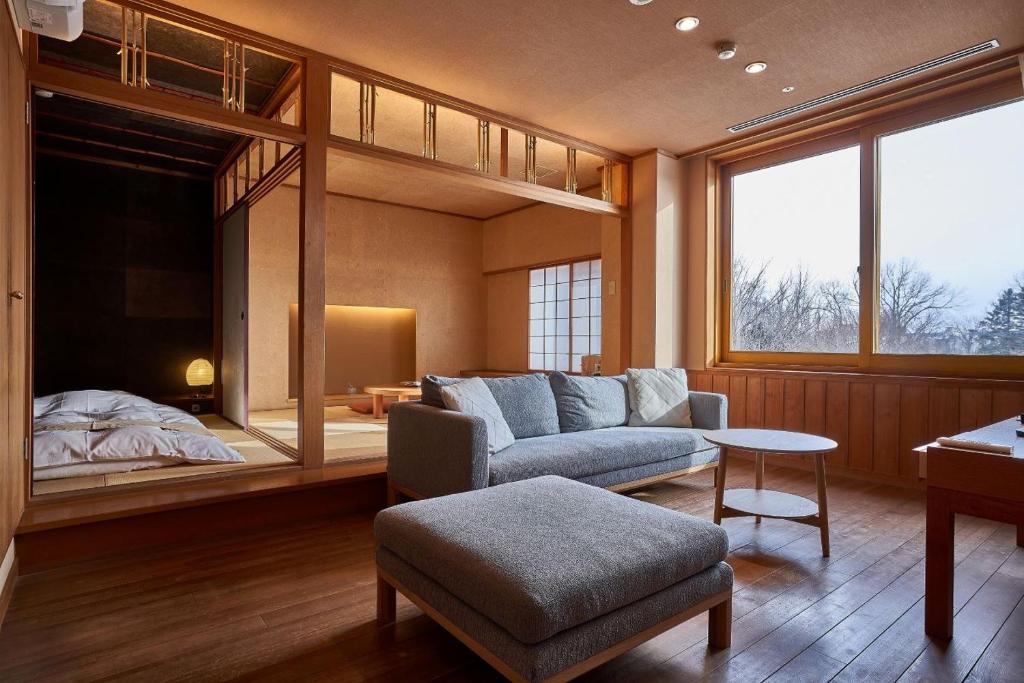 un salon avec un canapé et un lit dans l'établissement Sanyoan, à Otofuke