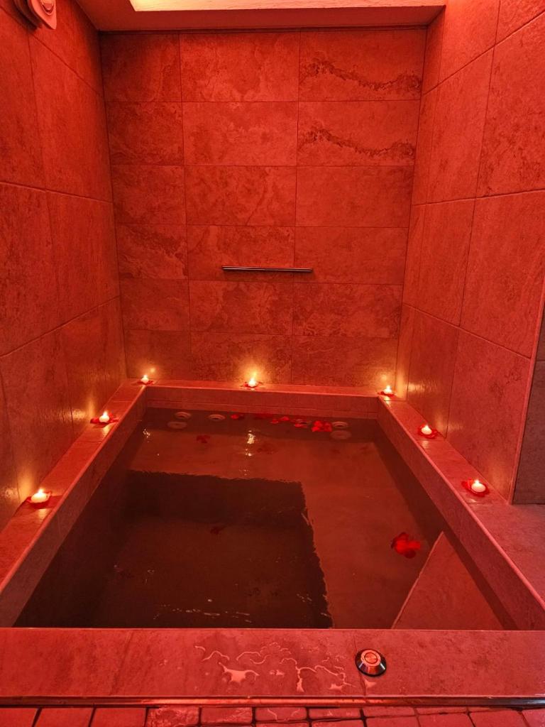 une baignoire avec des lumières dans une pièce rouge dans l'établissement LUXUITE Spa con Piscina o Jacuzzi, à Alberobello