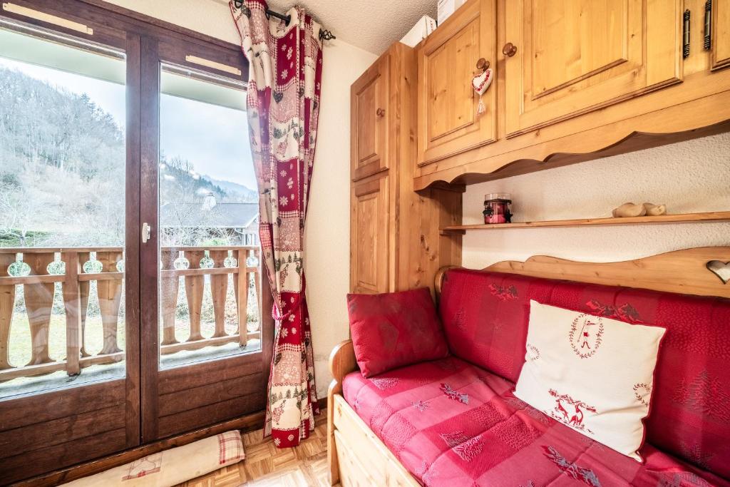 - un salon avec un canapé rouge et une fenêtre dans l'établissement Morillon - Studio 4 personnes, à Morillon