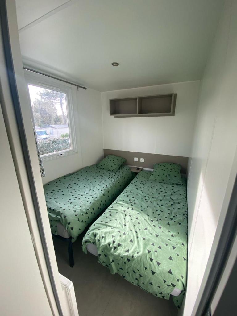 deux lits dans une petite pièce avec une fenêtre dans l'établissement mobil home 394 - Domaine de Kerlann, à Pont-Aven