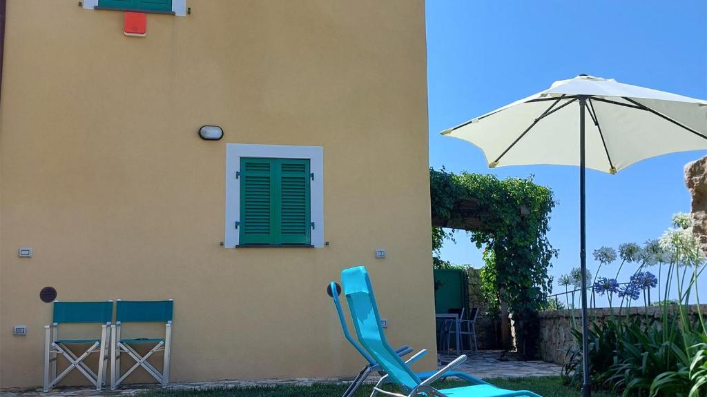 2 chaises et un parasol à côté d'un bâtiment dans l'établissement Miralunga la Villetta, à Lerici