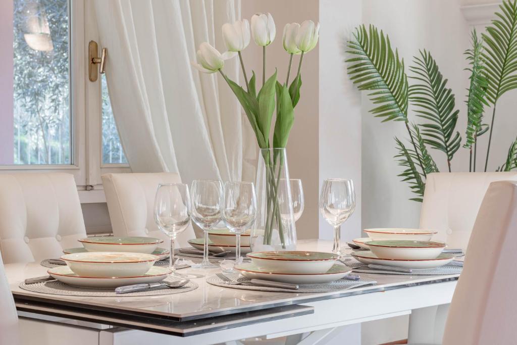 - une table à manger avec des assiettes, des verres et des fleurs dans l'établissement H11 [Villa Conchiglia] Piscina - Garage, à Castellaro