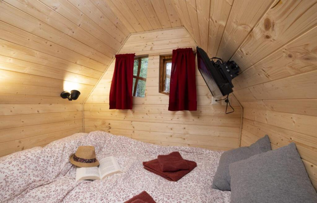 - une chambre avec un lit avec un chapeau et des livres dans l'établissement Camping USHUAÏA Villages Au Bois Joli, à Andryes