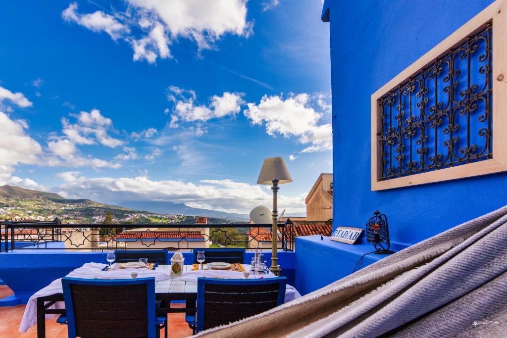 un restaurant avec un mur bleu, des tables et des chaises dans l'établissement Ryad A&B Sarai, à Chefchaouen