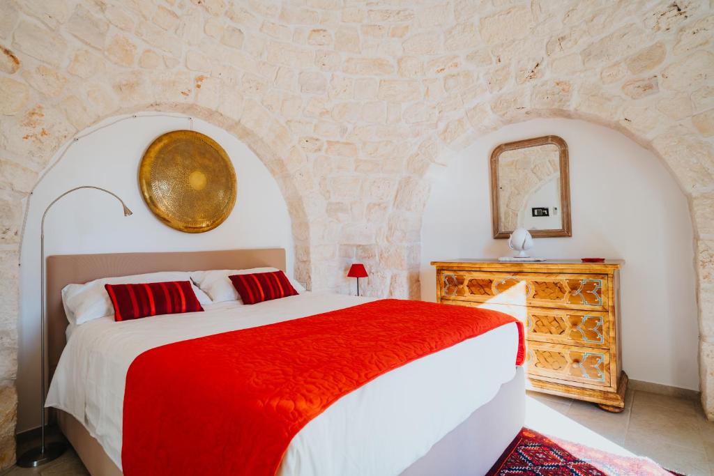 une chambre avec un grand lit et un mur en pierre dans l'établissement Trullo del Benessere, à Martina Franca