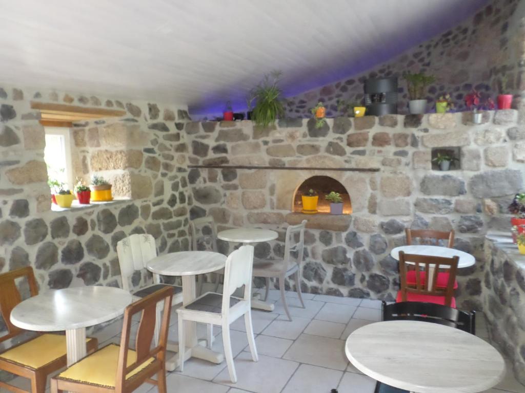 Cette chambre est dotée de tables, de chaises et d'un mur en pierre. dans l'établissement Nuits D'y Cîmes : Nuit Insolite Bulle, SPA, à Jaunac