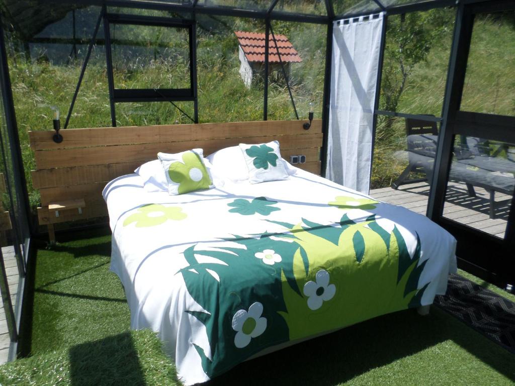 - un lit avec une couette verte et blanche et des fleurs dans l'établissement Nuits D'y Cîmes : Nuit Insolite Bulle, SPA, à Jaunac