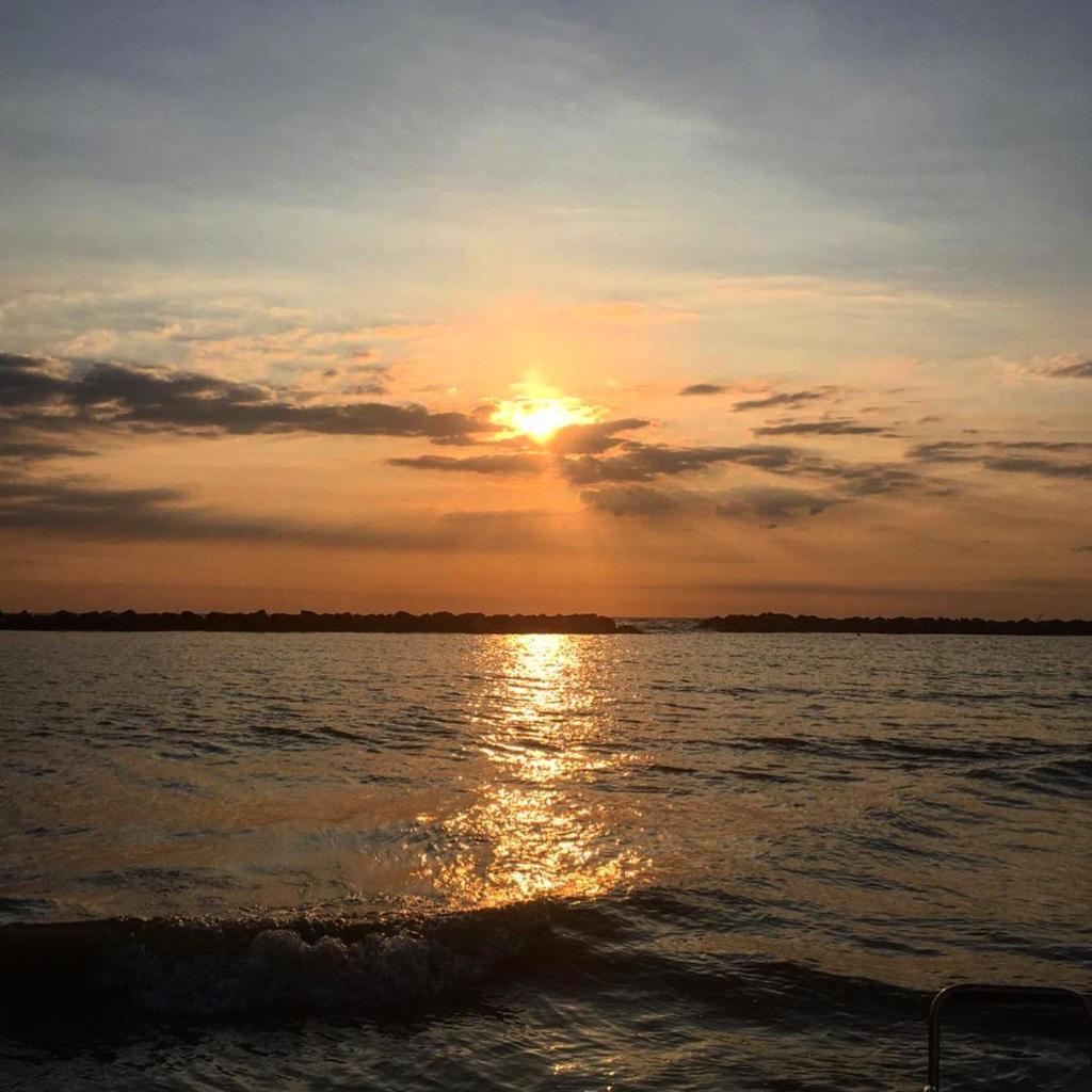 un coucher de soleil sur un plan d'eau avec le soleil couchant dans l'établissement Hotel Sandra, à Gatteo a Mare