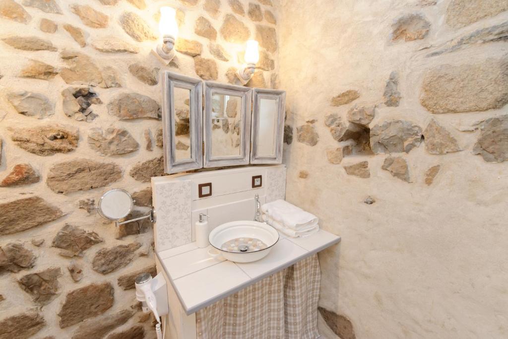 une salle de bain avec un lavabo et un mur en pierre dans l'établissement Nuits D'y Cîmes : Nuit Insolite Bulle, SPA, à Jaunac 37 autres photos