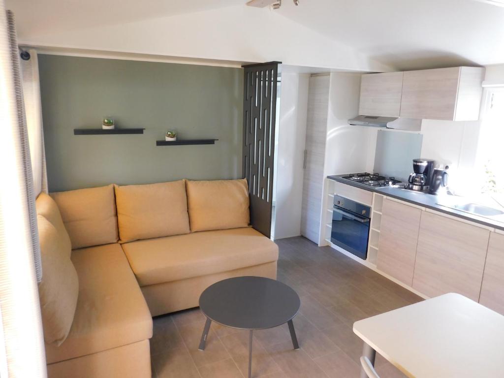 un salon avec un canapé et une table dans une cuisine dans l'établissement Domaine de Kerlann 4 étoiles - MOBIL HOME 2 CHAMBRES - 2 SDB - 315, à Pont-Aven