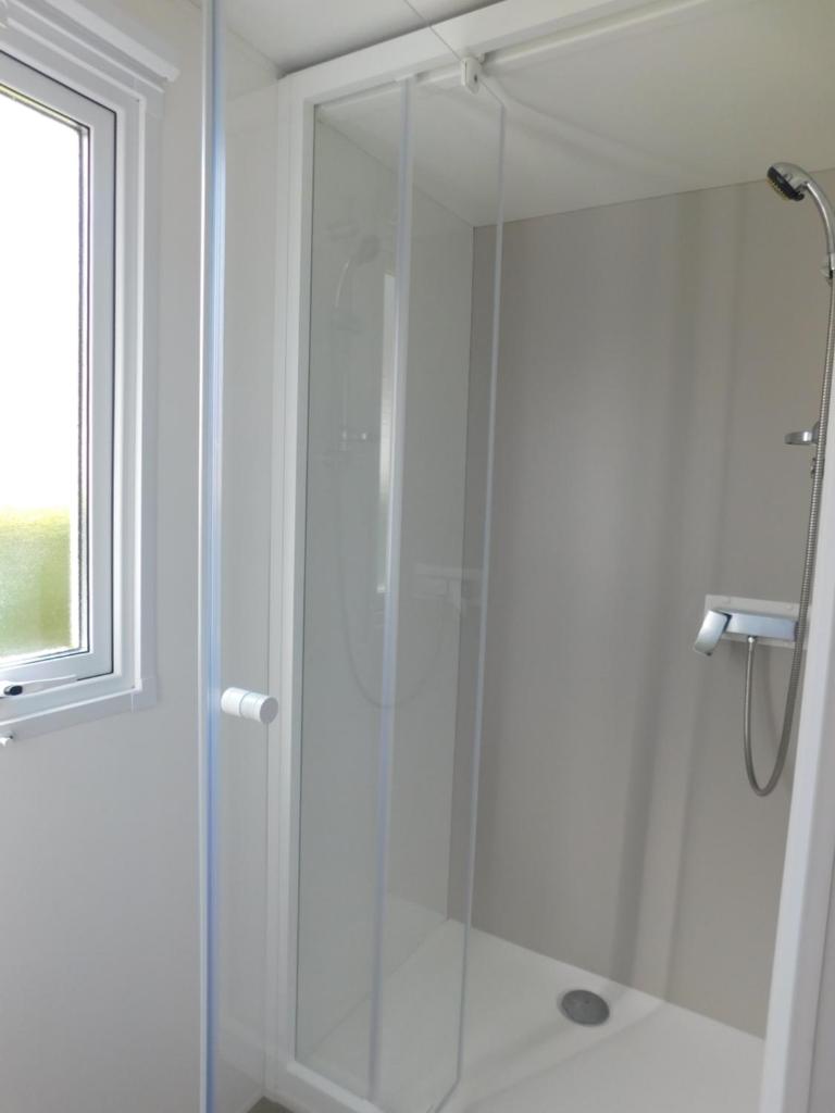 une douche avec une porte vitrée dans une salle de bain dans l'établissement Domaine de Kerlann 4 étoiles - MOBIL HOME 2 CHAMBRES - 2 SDB - 315, à Pont-Aven 3 autres photos