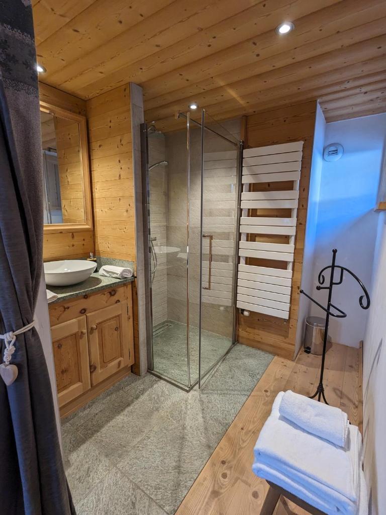 une salle de bain avec une douche en verre et un lavabo dans l'établissement Chalet Lè Lodzé - Pieds des pistes, à La Rosière 37 autres photos