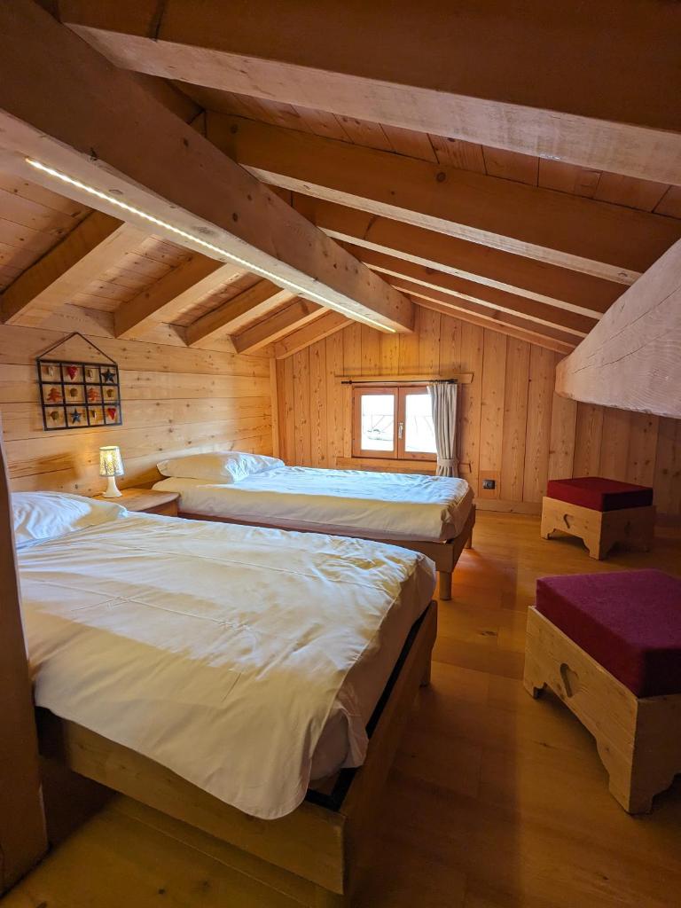 une chambre avec deux lits dans une cabane en rondins dans l'établissement Chalet Lè Lodzé - Pieds des pistes, à La Rosière