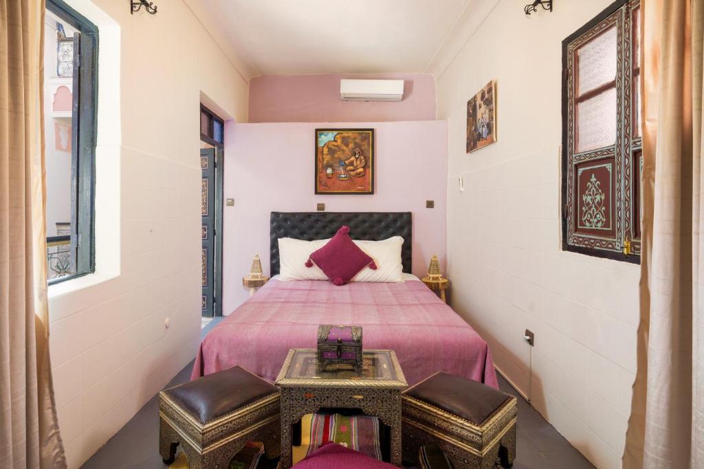 une chambre avec un lit avec deux chaises et une table dans l'établissement RIAD MAMAHOUSE, à Marrakech