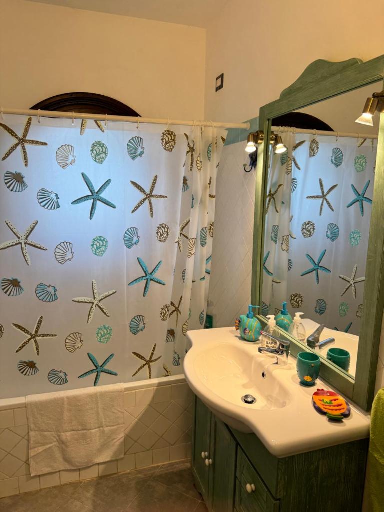 une salle de bain avec un lavabo et un rideau de douche dans l'établissement Villa Holiday Park Stintino - Piscina privata ed esclusiva, à Stintino
