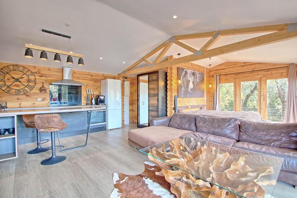 un salon avec un canapé et une cuisine dans l'établissement romantique cabane perchée avec spa vue panoramique Le Mas des faraches, à Solliès-Toucas