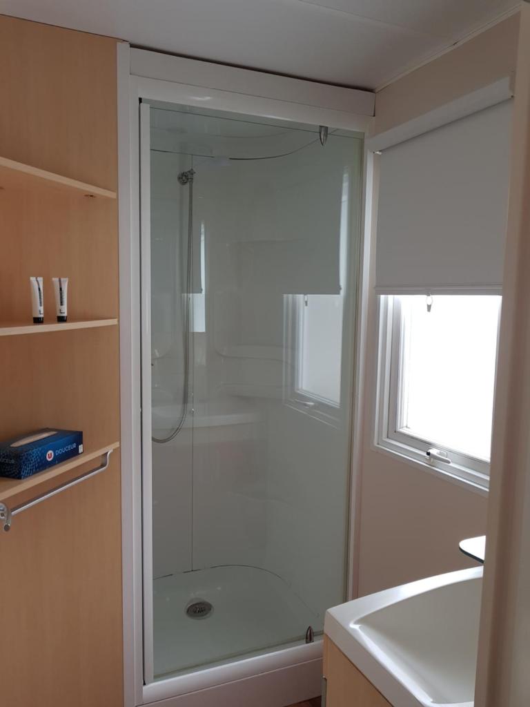 une douche avec une porte vitrée dans une salle de bain dans l'établissement Camping Le Ried *** Mobil Home Cosy 3 chambres Proche Europa Park Rulantica, à Boofzheim