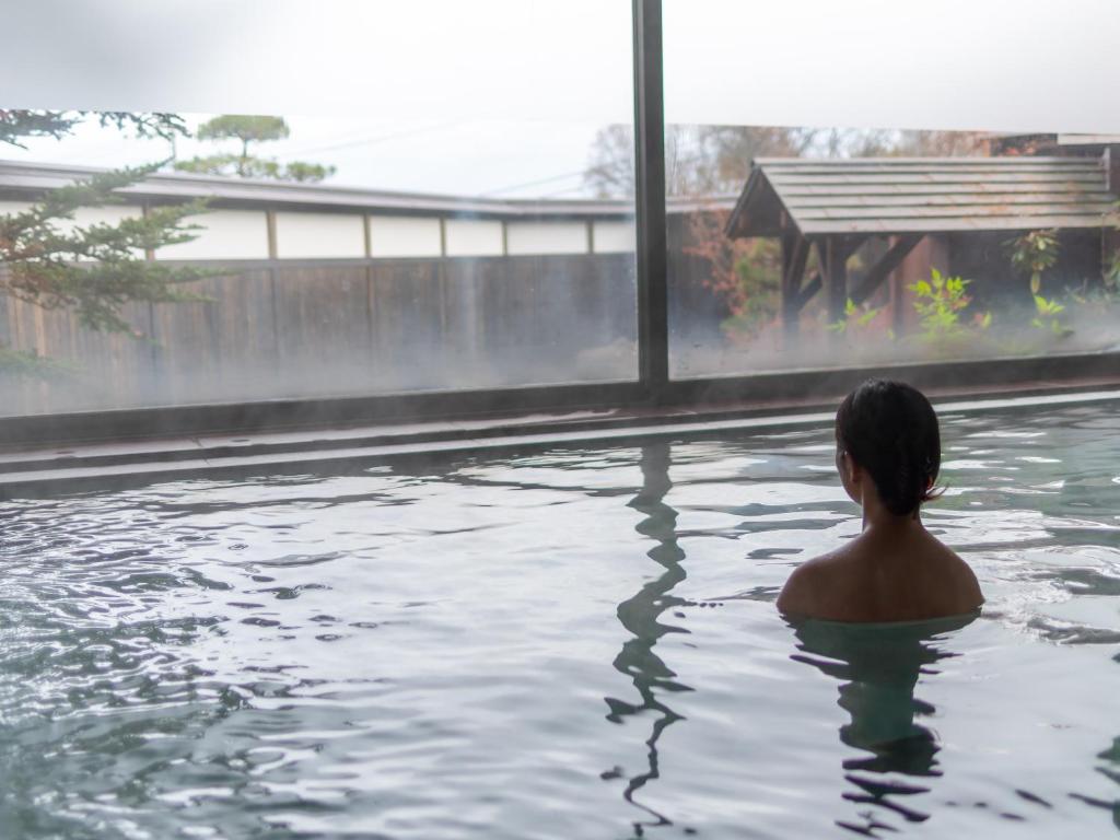 un homme assis dans un bassin d'eau dans l'établissement Kusatsu-onsen Hotel Resort, à Kusatsu