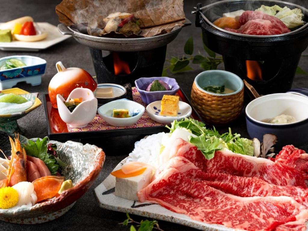 une table recouverte de différents types de nourriture sur les assiettes dans l'établissement Kusatsu-onsen Hotel Resort, à Kusatsu