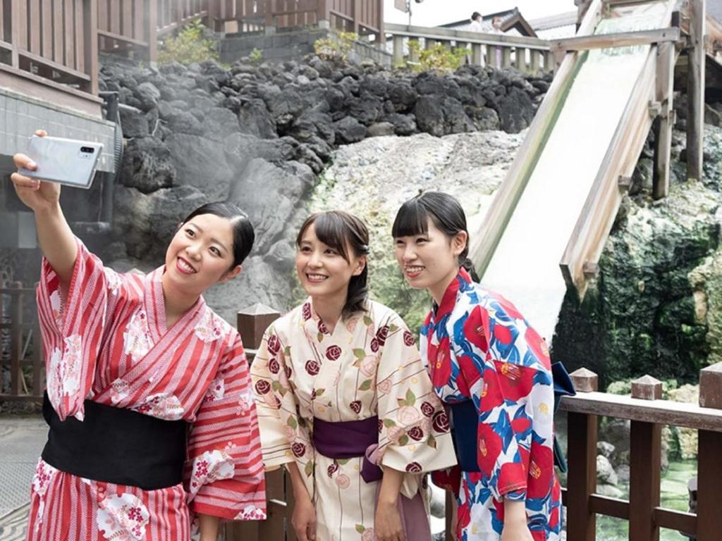 trois femmes en kimonos debout devant une cascade dans l'établissement Kusatsu-onsen Hotel Resort, à Kusatsu