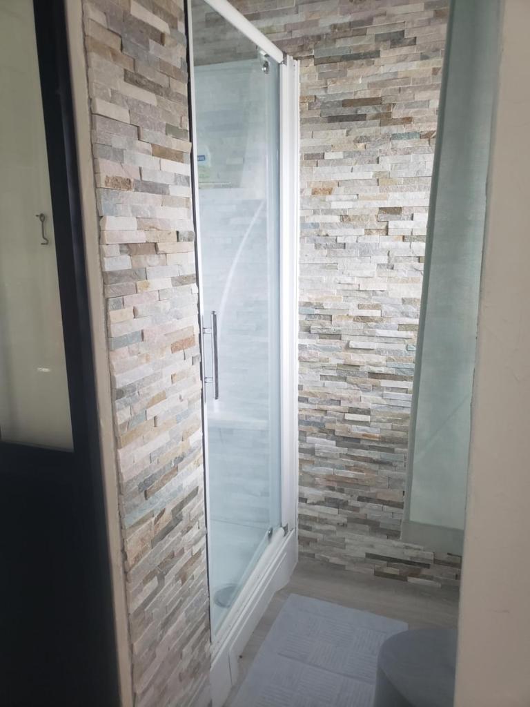 La salle de bains est pourvue d'une douche et d'un mur en pierre. dans l'établissement Yourte atypique entre Lyon et Grenoble ! Vue sur les montagnes., à Nohant-en-Graçay 14 autres photos
