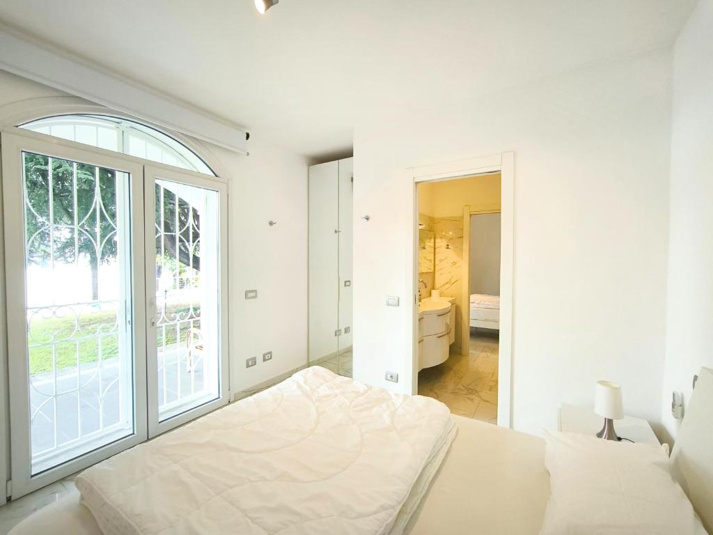 une chambre blanche avec un lit et une grande fenêtre dans l'établissement Casa Blanca, à Lesa