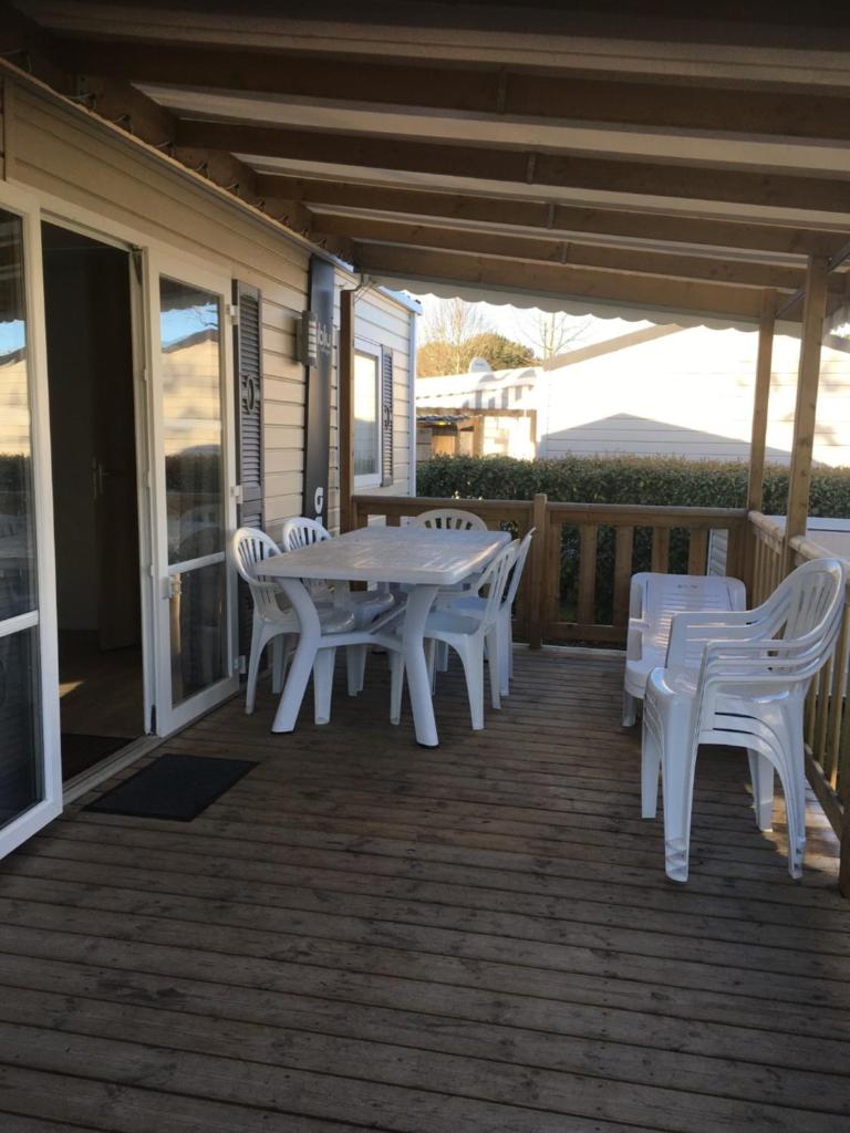 une table et des chaises blanches sur une terrasse dans l'établissement MOBIL HOME 2 CHAMBRES CLIMATISE, à Gastes