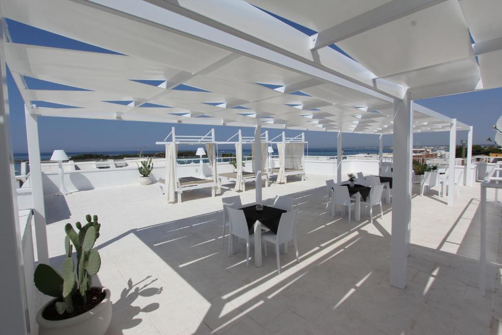 - un pavillon avec des chaises et des tables blanches et l'océan dans l'établissement Hotel Paladini, à Porto Cesareo