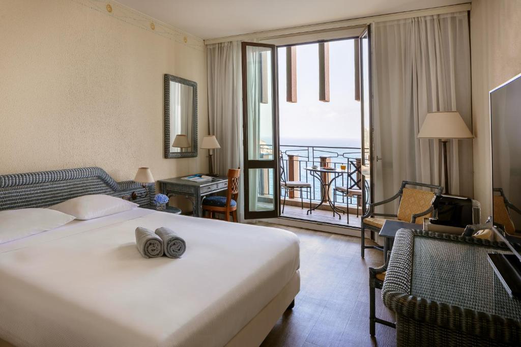 une chambre d'hôtel avec un lit et un balcon dans l'établissement UNA Hotels Capotaormina, à Taormine