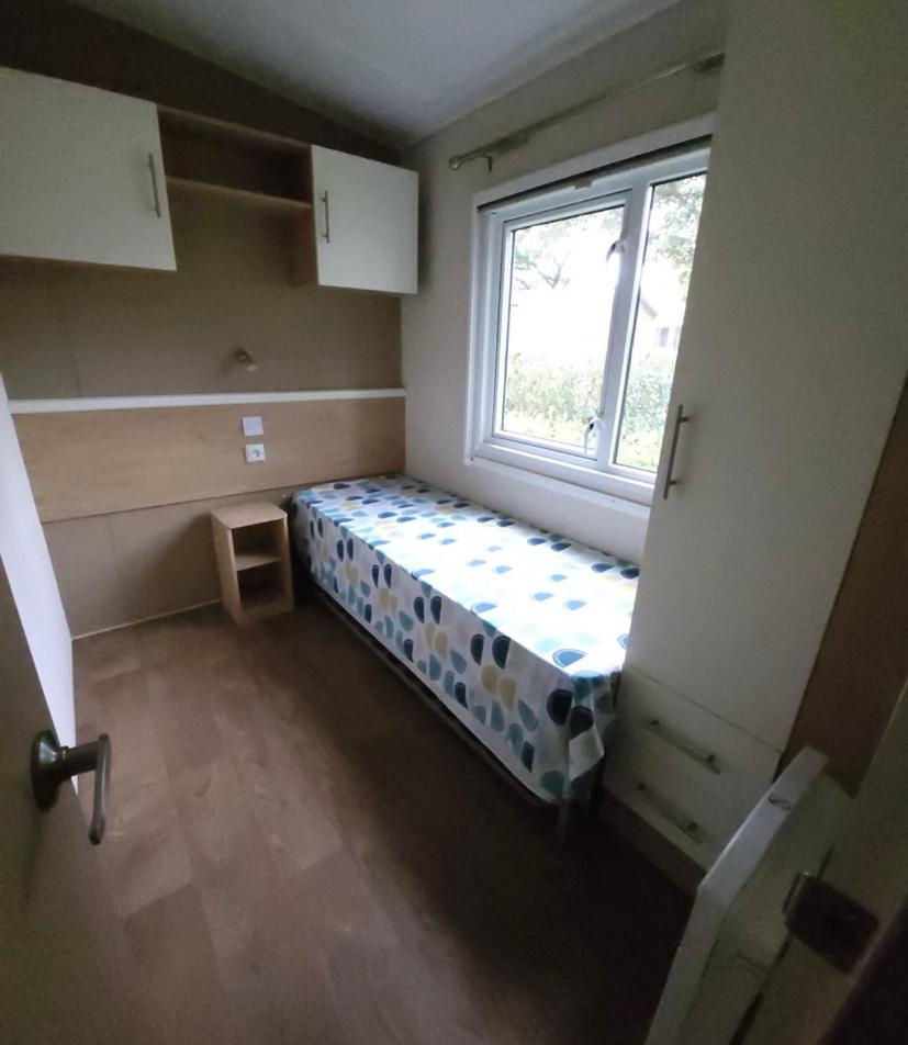Cette petite chambre dispose d'un lit en face d'une fenêtre. dans l'établissement Mobilhome - Kedidrouz du Léon - Kerlann - Pont Aven, à Pont-Aven