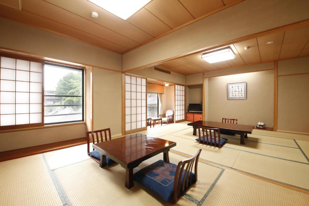 une pièce avec une table, des chaises et des fenêtres dans l'établissement Wakamatsu Honten, à Narita