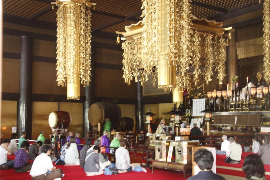 une foule de personnes assises dans une pièce ornée de lustres dans l'établissement Wakamatsu Honten, à Narita