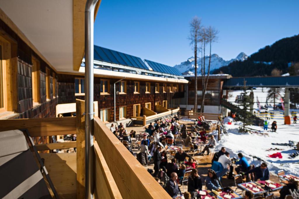 Une foule assise sur la neige devant un bâtiment dans l'établissement Marmotel & Spa, à Pra-Loup