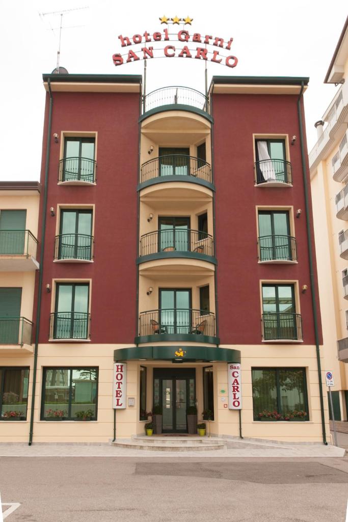 un bâtiment rouge avec une pancarte sur celui-ci dans l'établissement Hotel Garni San Carlo, à Lido di Jesolo