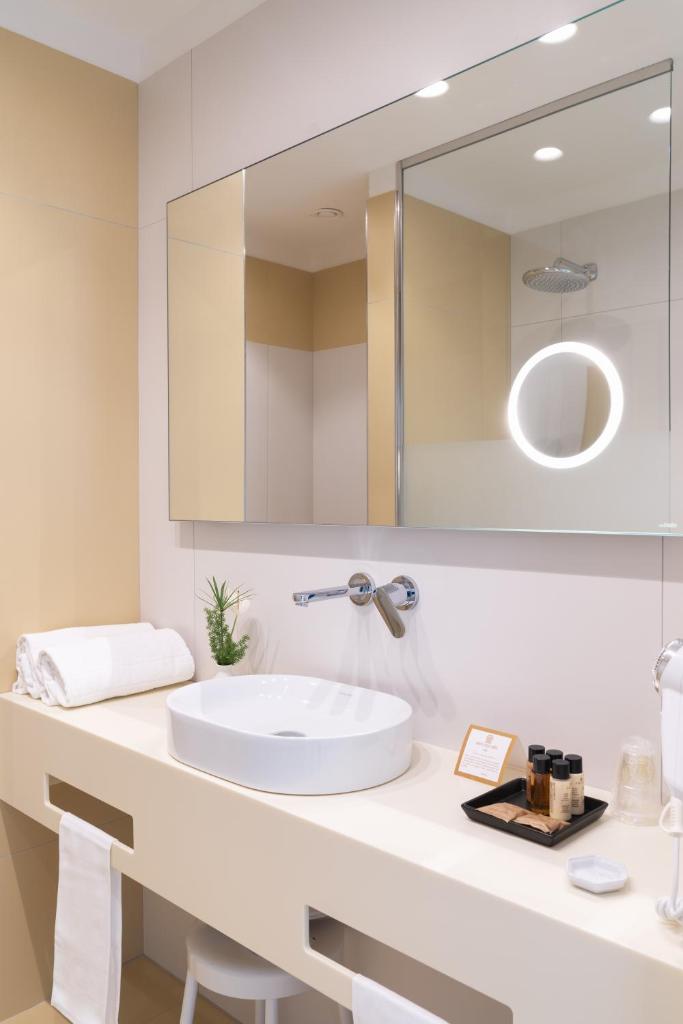 une salle de bain avec un lavabo et un grand miroir dans l'établissement Reginna Palace Hotel, à Maiori