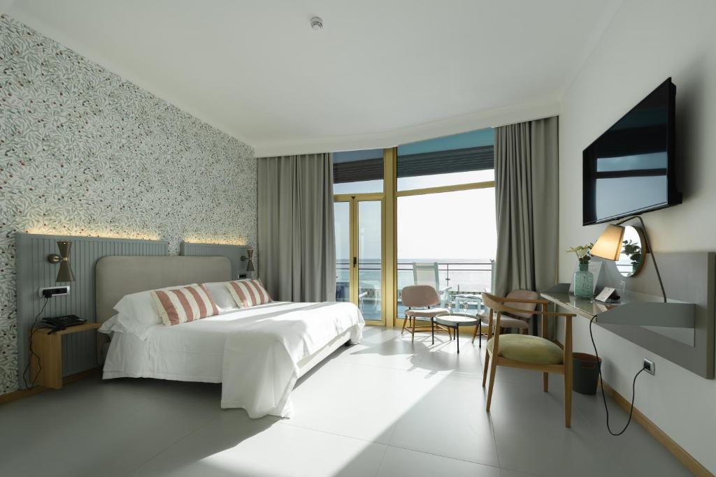 une chambre avec un lit, un bureau et une télévision dans l'établissement Reginna Palace Hotel, à Maiori