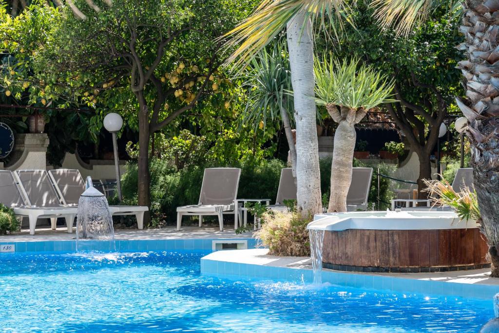 - une piscine avec des chaises et un palmier dans l'établissement Reginna Palace Hotel, à Maiori