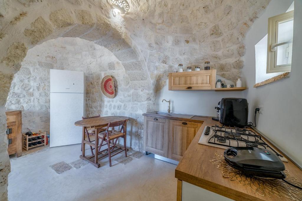 une cuisine avec un mur en pierre et un comptoir dans l'établissement Trulli Magalò, à Ceglie Messapica