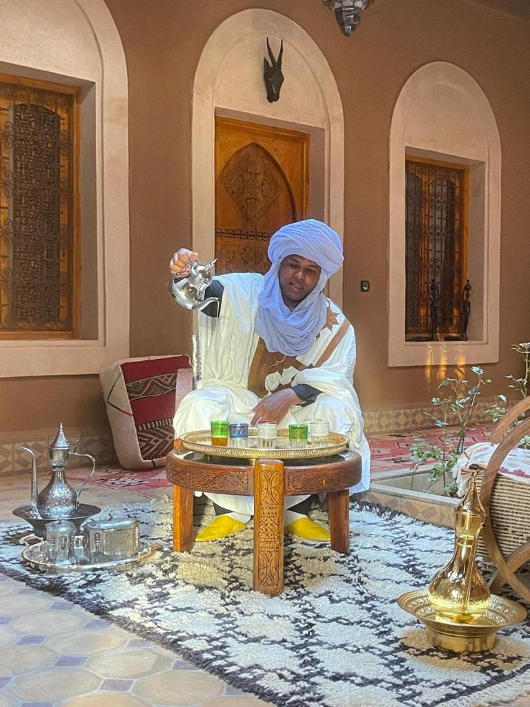 Un homme assis sur une table dans une pièce dans l'établissement Riad Dar Susan - Authentic Stay in Zagora, à Zagora