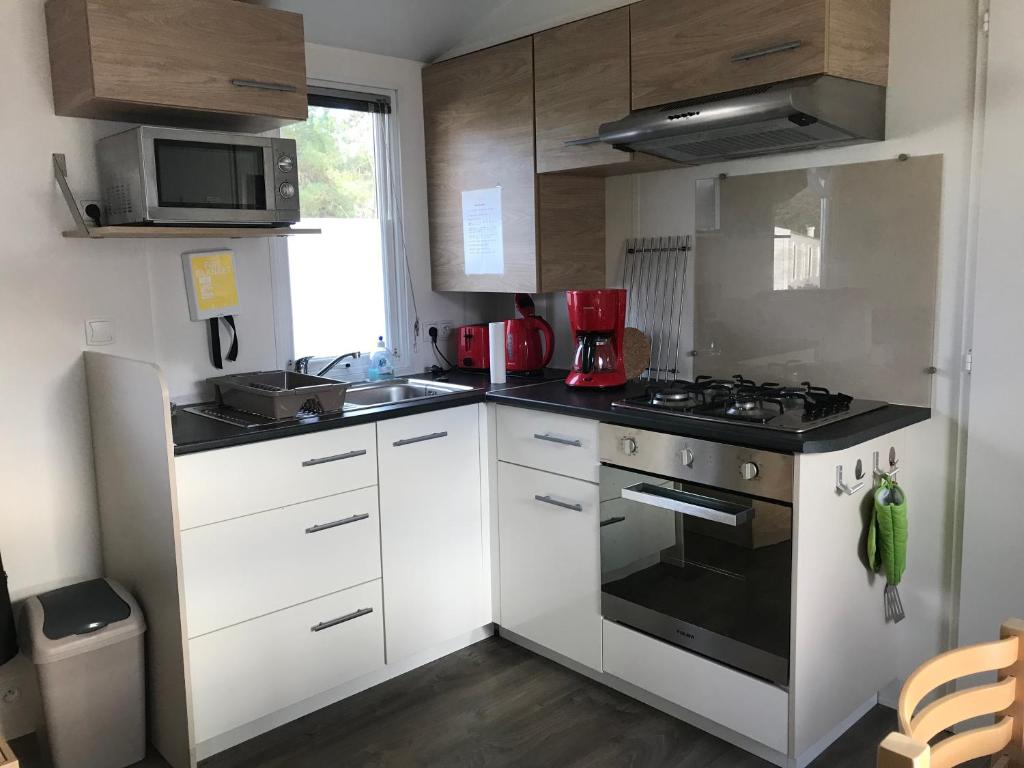 une cuisine avec des armoires blanches et un four à plaques de cuisson dans l'établissement MOBIL HOME 2 CHAMBRES 1 SDB - DOMAINE DE KERLANN, à Pont-Aven